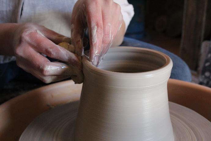 person holding brown clay pot